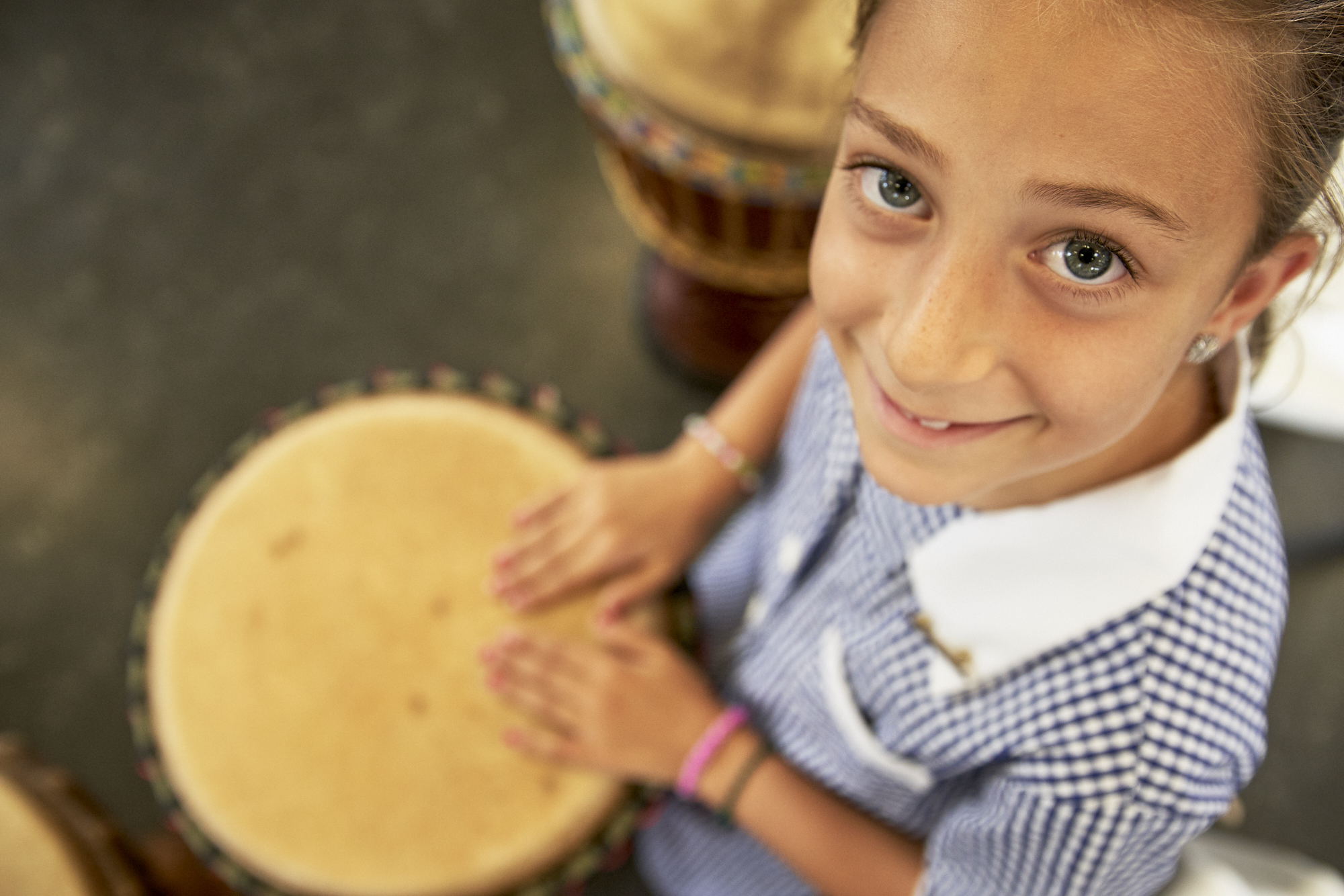 Girl playing drum, looking up at camera