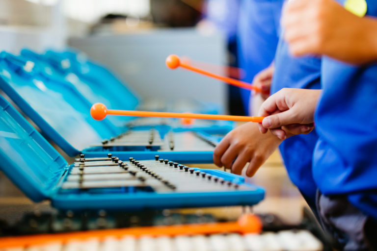 primary school student playing glockenspiel instrument in arts learning lesson